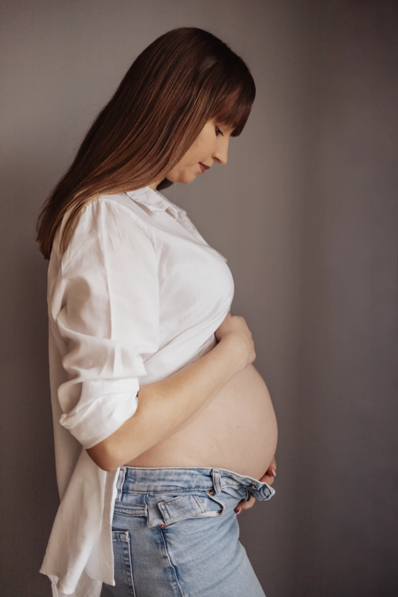 Sesja ciążowa — delikatny portret ciążowy w stonowanej, studyjnej scenerii